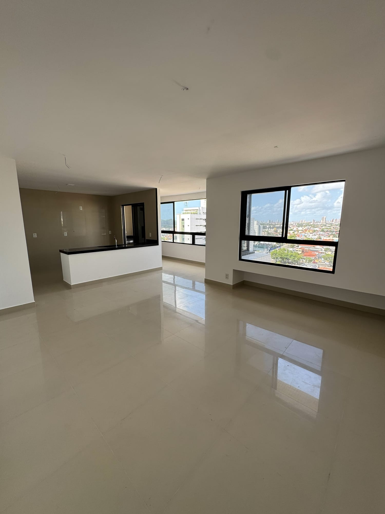 Sala de estar e jantar integrada à cozinha americana do apartamento Graciliano Ramos, com vista para Natal