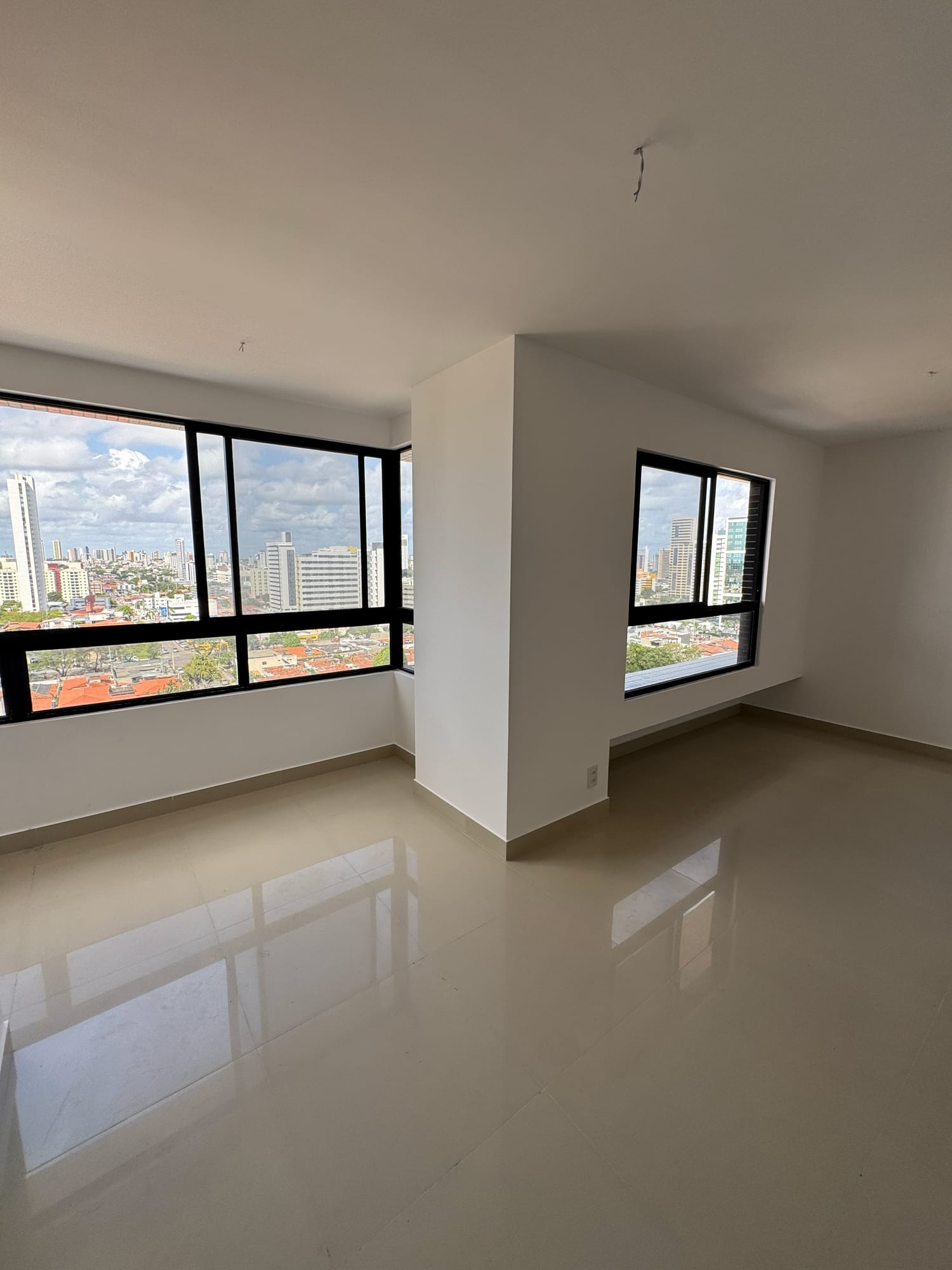 Sala de estar do apartamento Graciliano Ramos, com esquadrias amplas e vista da cidade