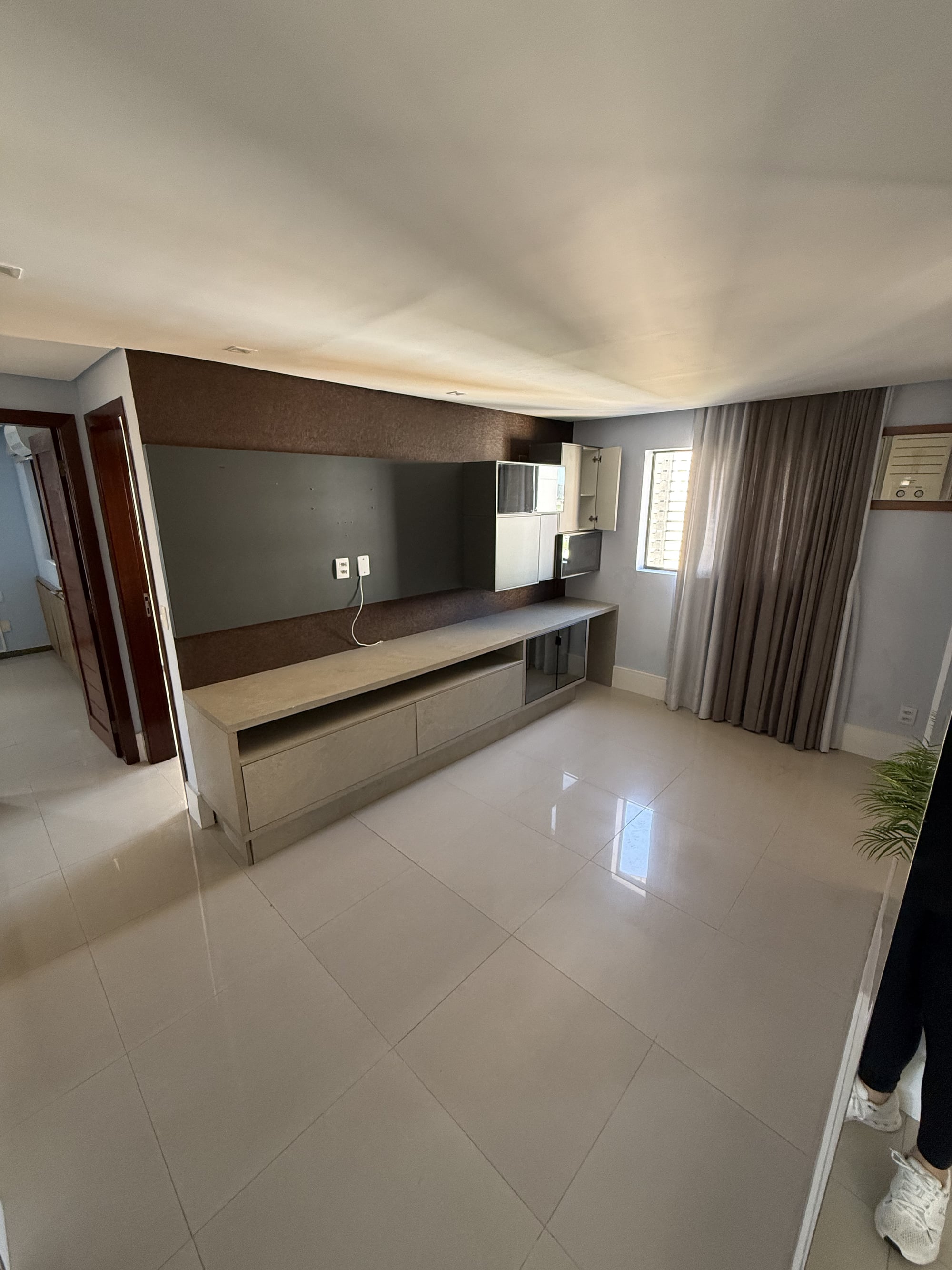 Sala de estar do apartamento no Residencial Therra Luna, com painel de TV e ar-condicionado